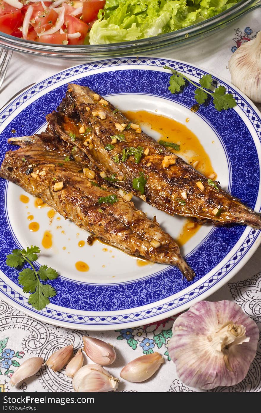 Close up view of a Portuguese meal of Wahoo grilled fish with annatto sauce and Mediterranean salad. Close up view of a Portuguese meal of Wahoo grilled fish with annatto sauce and Mediterranean salad.