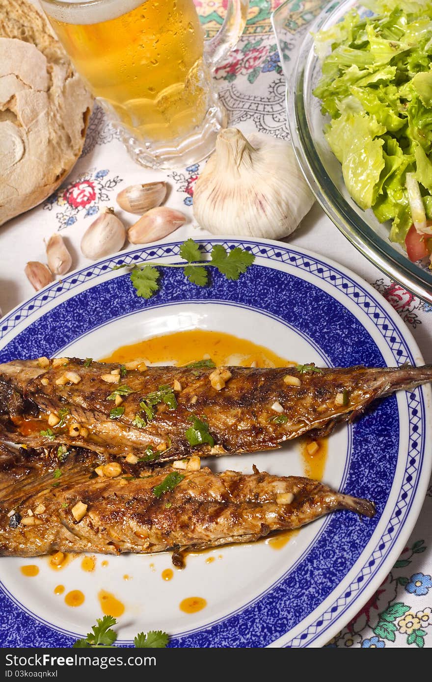 Close up view of a Portuguese meal of Wahoo grilled fish with annatto sauce and Mediterranean salad. Close up view of a Portuguese meal of Wahoo grilled fish with annatto sauce and Mediterranean salad.