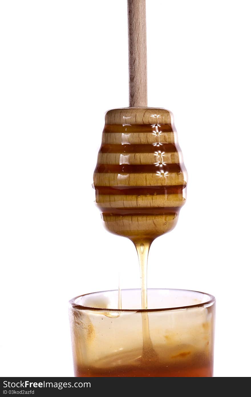 Close up view of a glass of honey with dipper isolated on a white background.