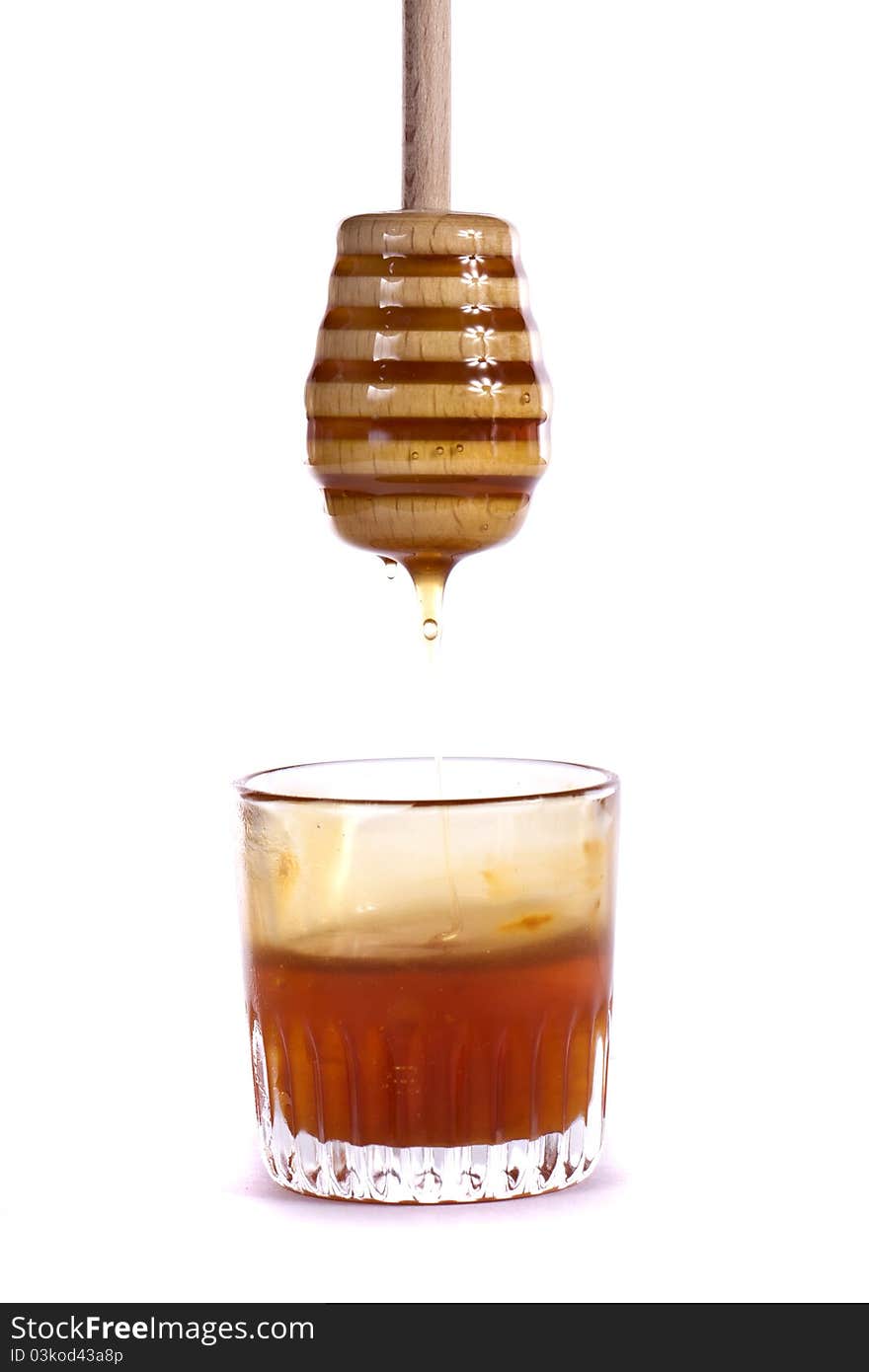 Close up view of a glass of honey with dipper isolated on a white background.