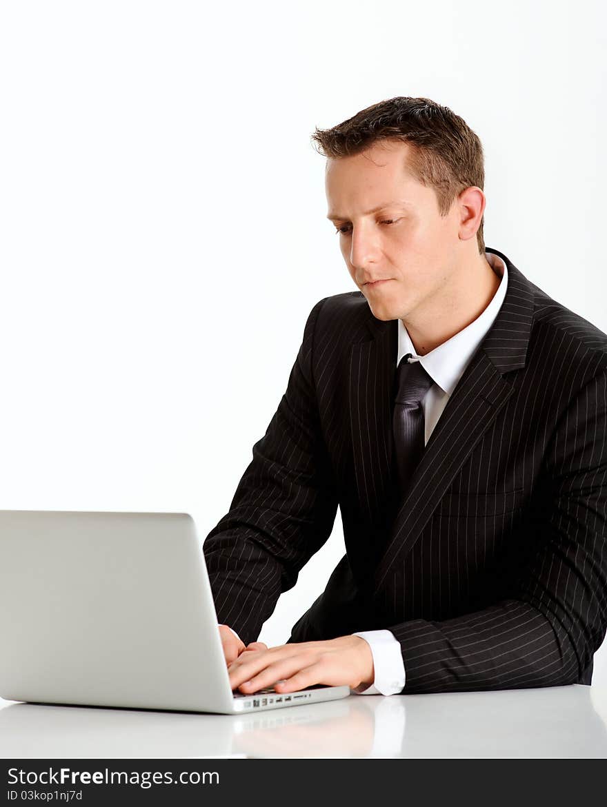 Attractive caucasian professional in a business suit works on his laptop. Attractive caucasian professional in a business suit works on his laptop