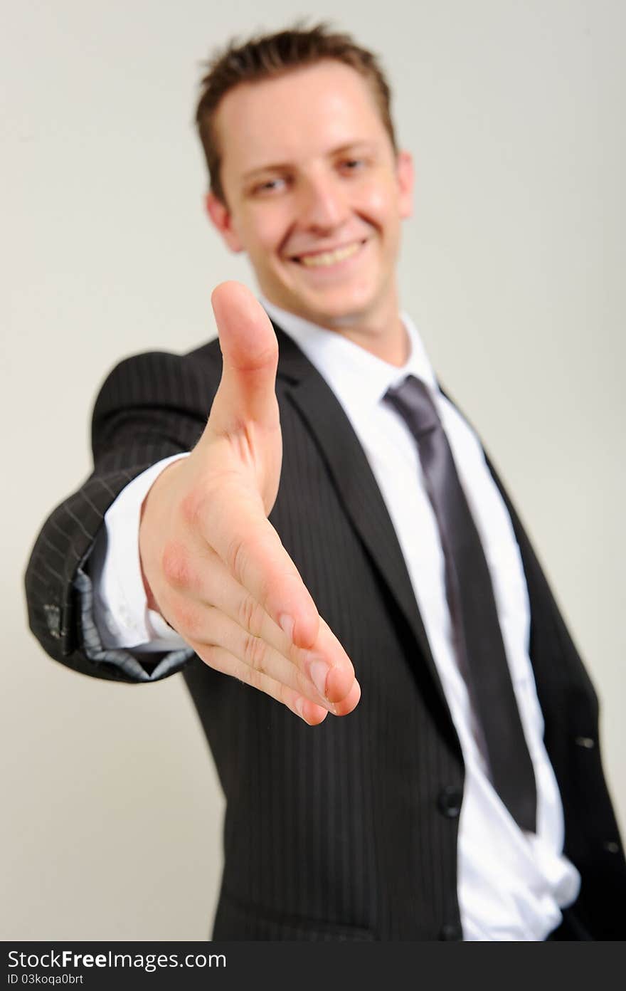 Attractive white associate stretches his arm out for a handshake to seal the deal. Attractive white associate stretches his arm out for a handshake to seal the deal