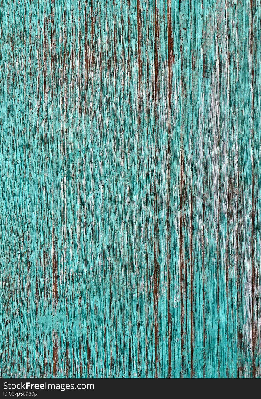 Green paint peeling from a wooden panel door showing the wood grain. Green paint peeling from a wooden panel door showing the wood grain