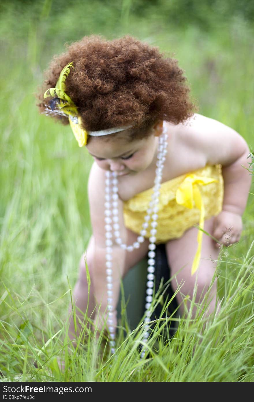 Cute toddler girl wearing a feather headband and a cute yellow petti romper