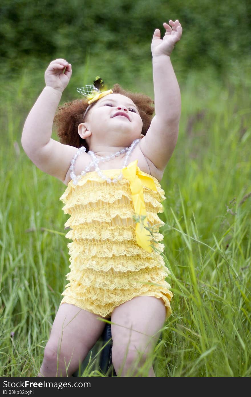 Cute toddler girl wearing a feather headband and a cute yellow petti romper