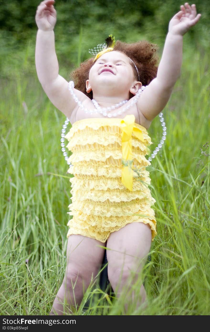 Cute toddler girl wearing a feather headband and a cute yellow petti romper