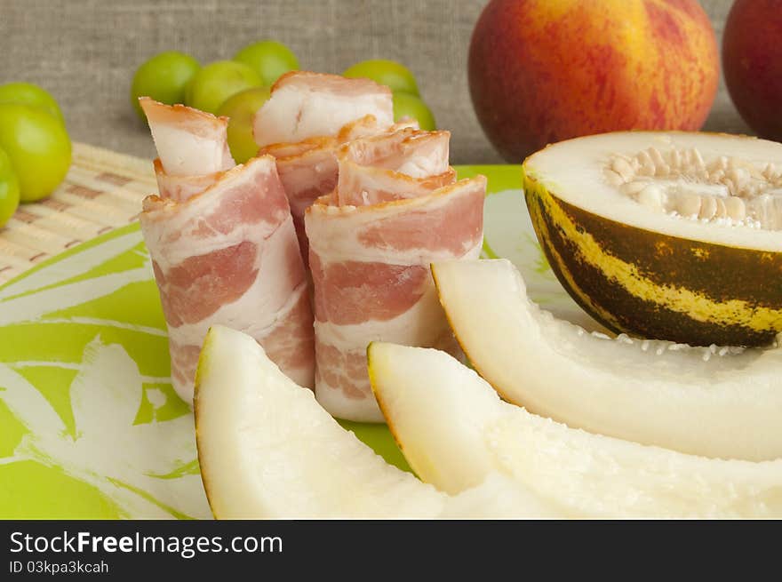 Ham with melon and peach on a green plate. Ham with melon and peach on a green plate