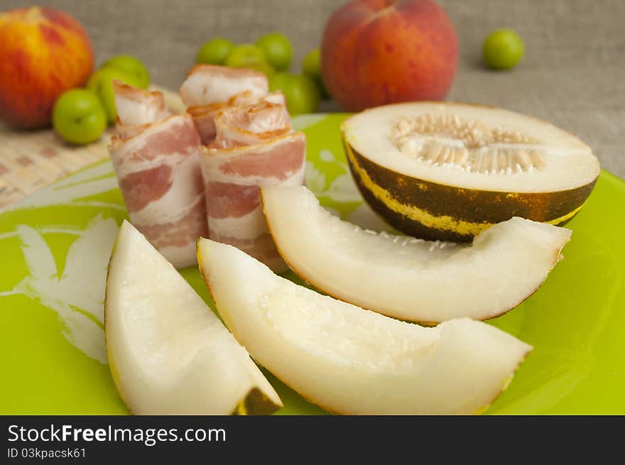 Ham with melon and peach on a green plate. Ham with melon and peach on a green plate