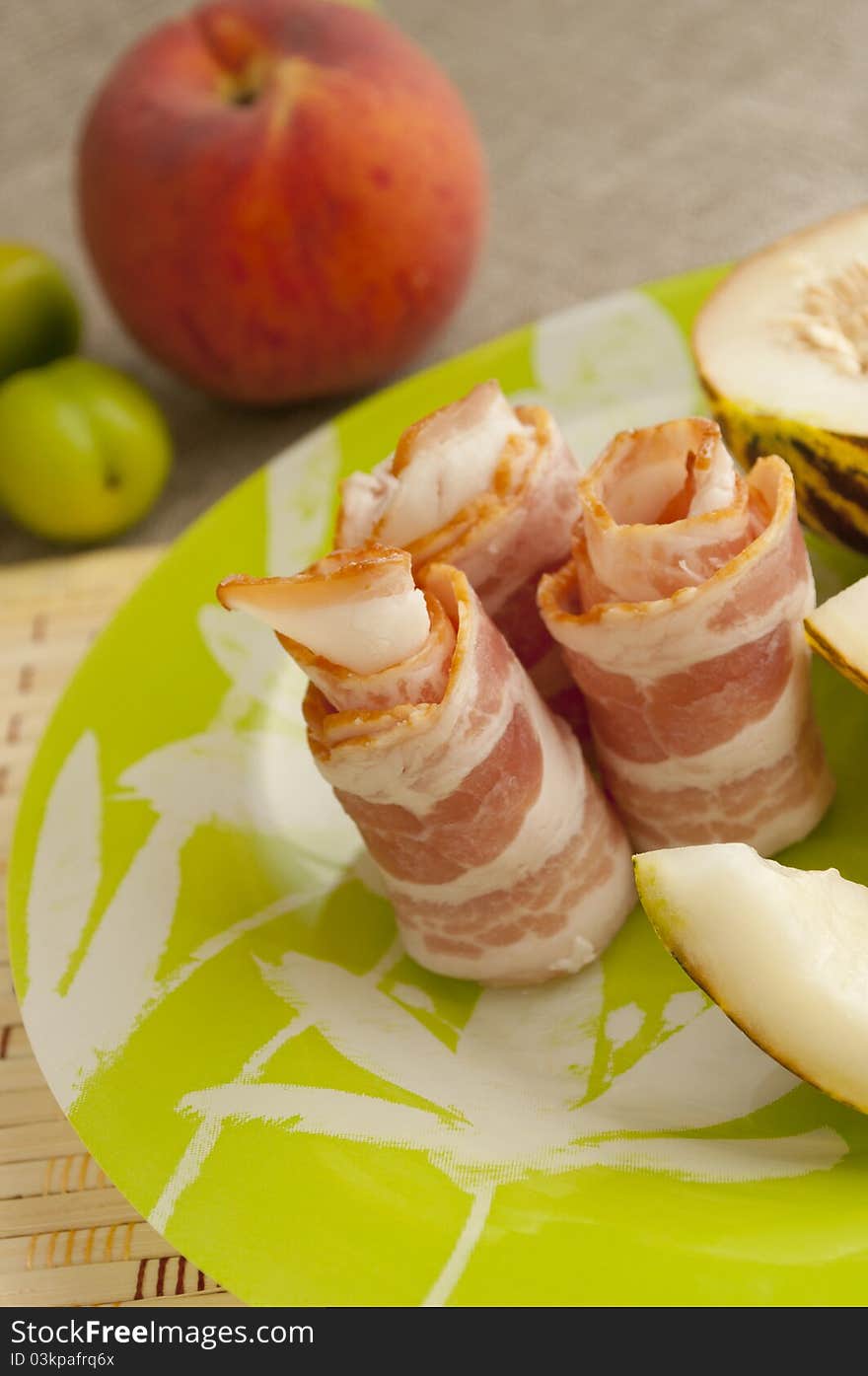 Ham with melon and peach on a green plate. Ham with melon and peach on a green plate