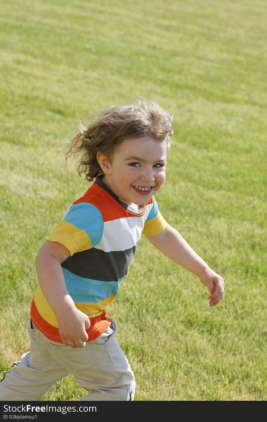 A happy boy is running on the lawn. A happy boy is running on the lawn.