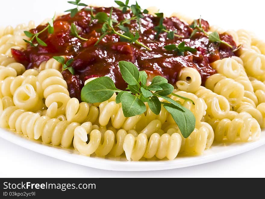 Fusilli pasta with tomato and vegetable sauce over white background