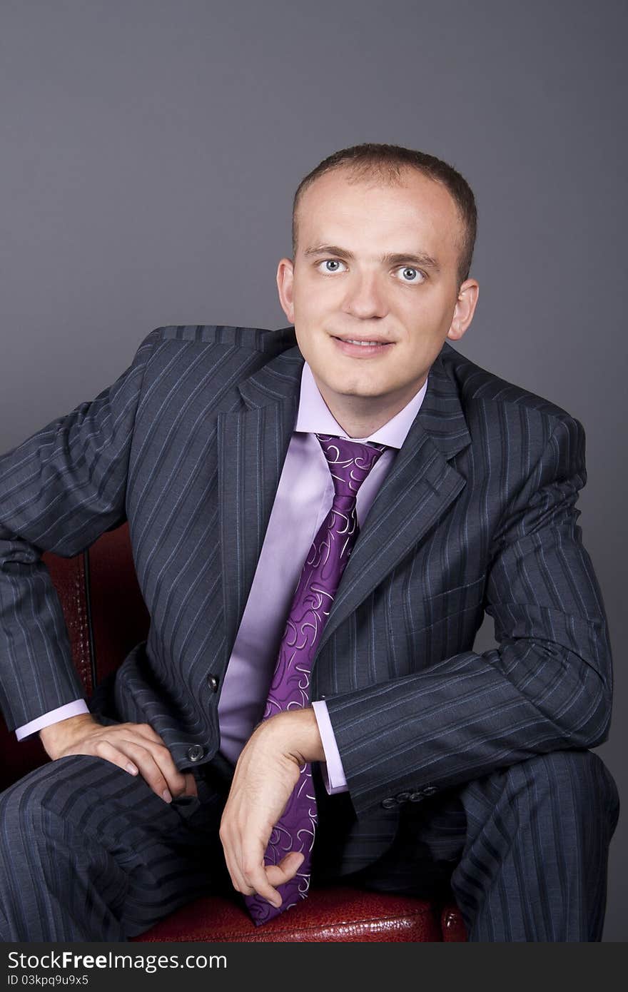 Thoughtful guy in a suit sitting on a red couch