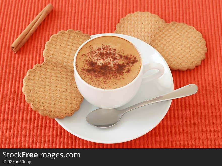 A cup of coffee with cinnamon and cookies