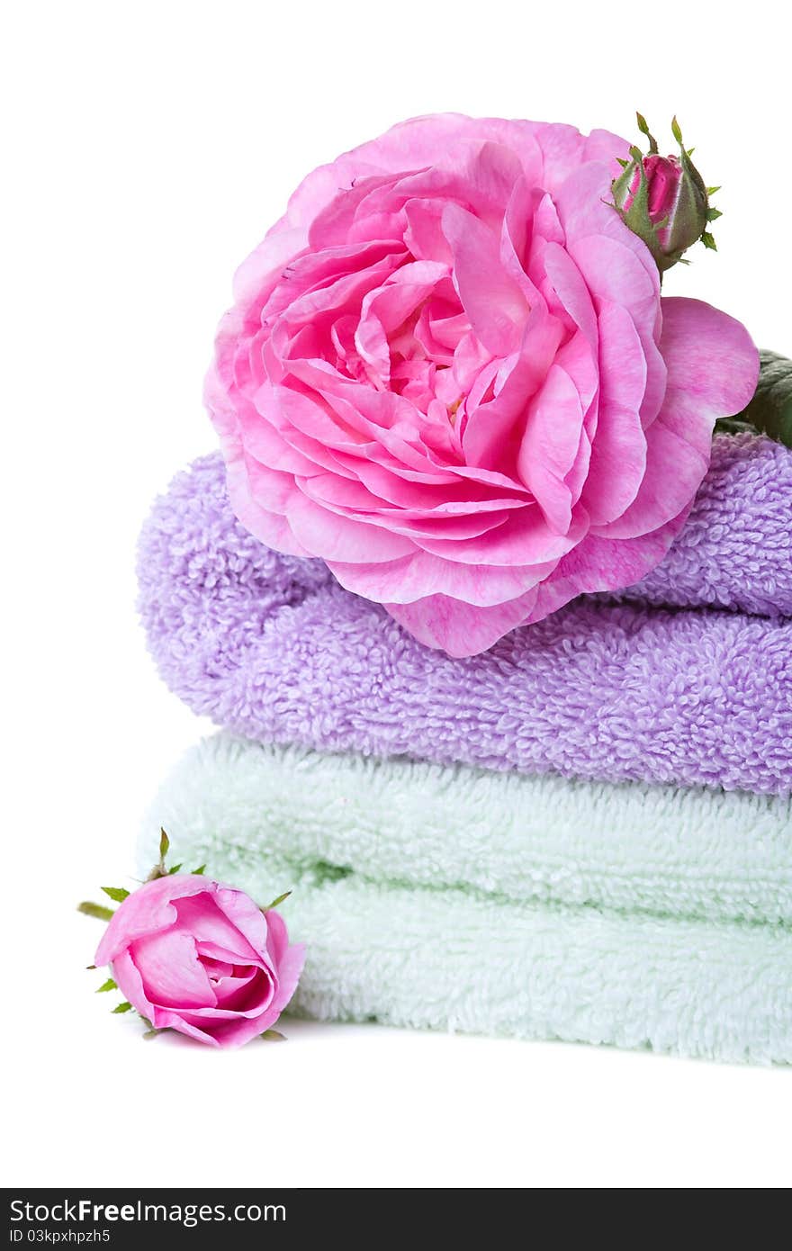 Stacked colorful towels with roses flower. Isolated over white