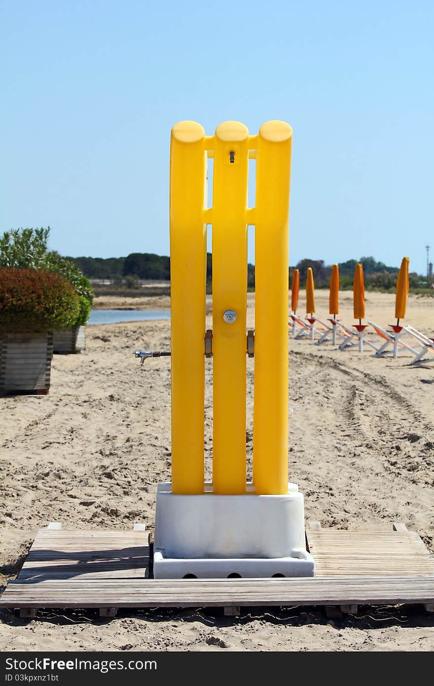 Yellow shower on the beach with sunshades in the background