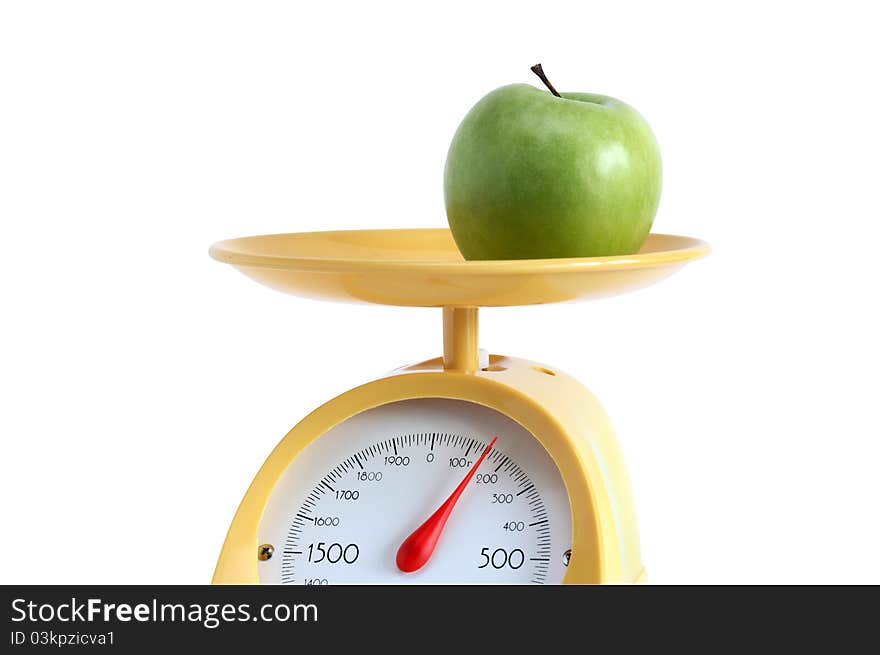 Green apple lying on yellow kitchen scale. Isolated on white background with clipping path. Green apple lying on yellow kitchen scale. Isolated on white background with clipping path