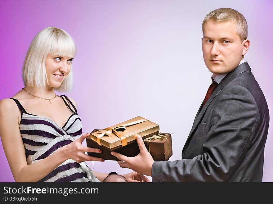 Beautiful young couple with a gift posing on a colored background. Beautiful young couple with a gift posing on a colored background