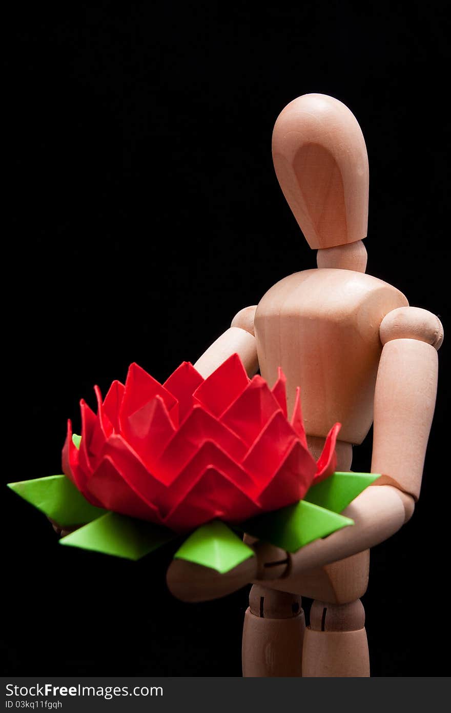 A wooden mannequin carrying hand-made paper flower. This photo made over black background but is not isolated. A wooden mannequin carrying hand-made paper flower. This photo made over black background but is not isolated.