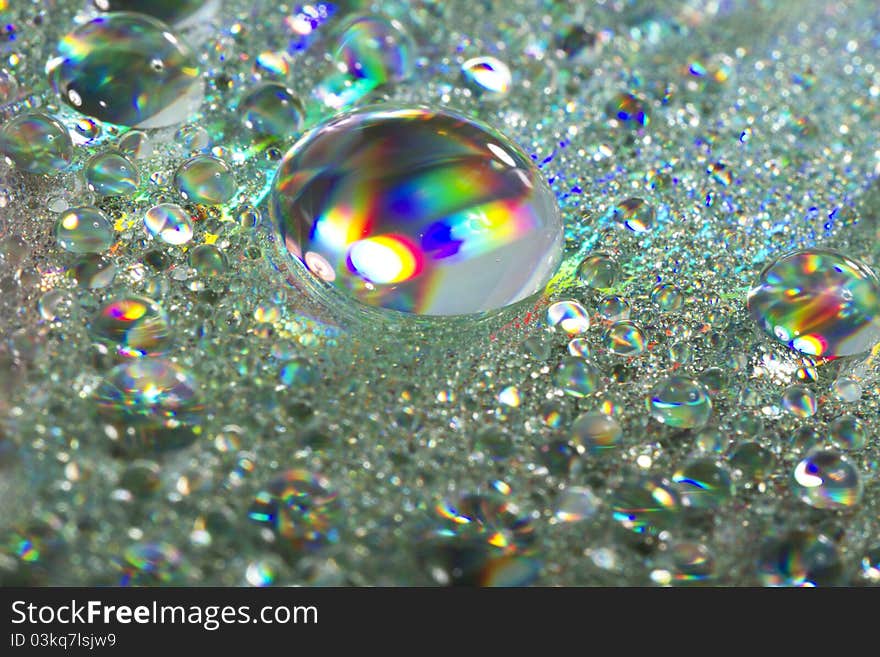 Close up view of many colorful and bright drops of water on a shiny surface. Close up view of many colorful and bright drops of water on a shiny surface.