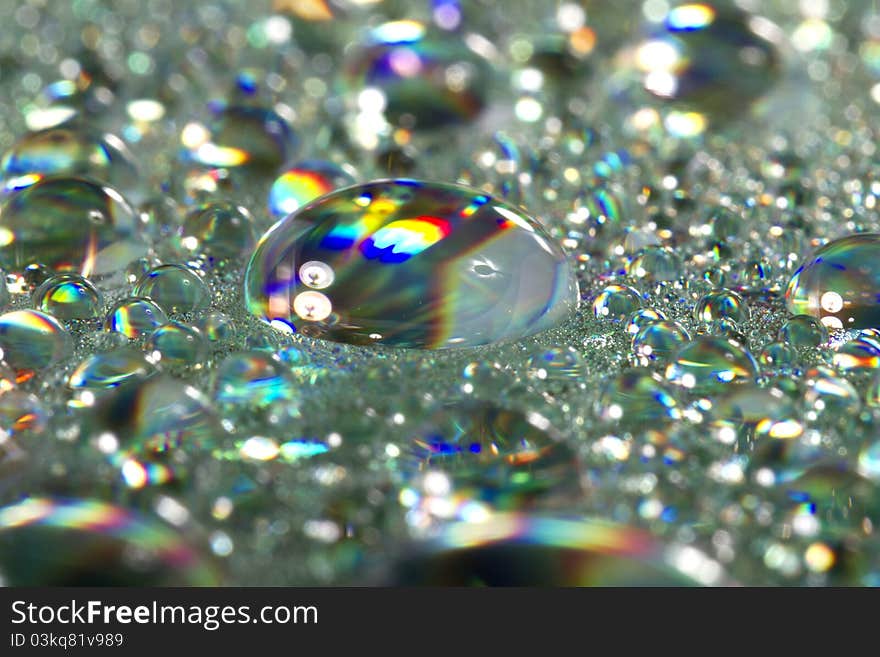 Close up view of many colorful and bright drops of water on a shiny surface. Close up view of many colorful and bright drops of water on a shiny surface.