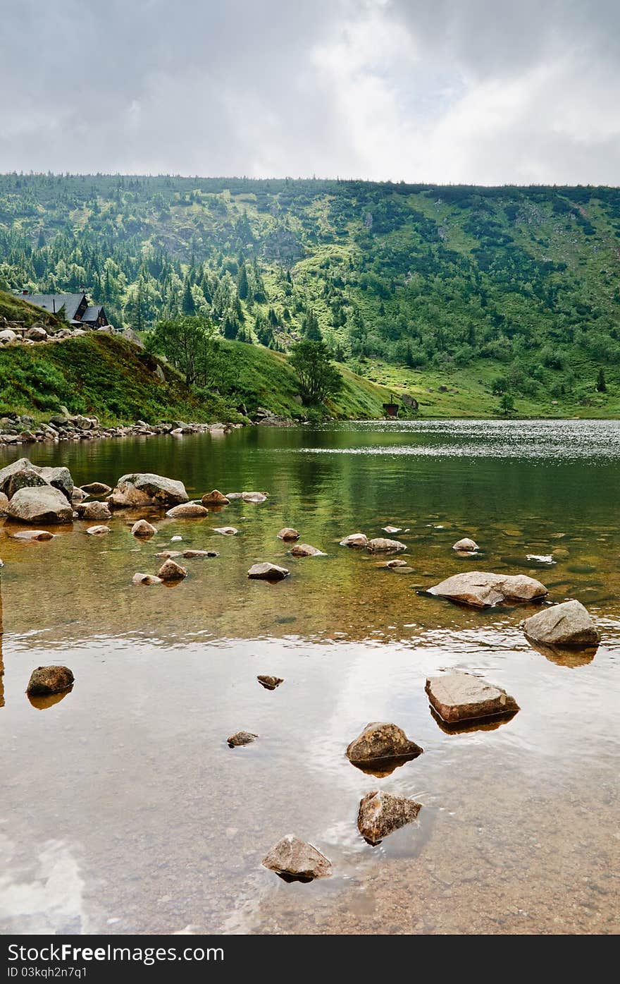 Picture shows a mountain lake and mountain hut in the fog