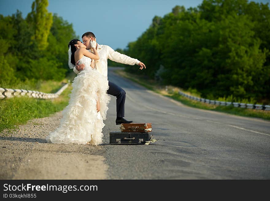 Newlywed couple hitchhiking on a road