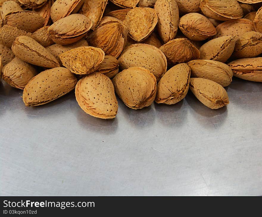 A shot of a bunch of almonds with its shell on a tray