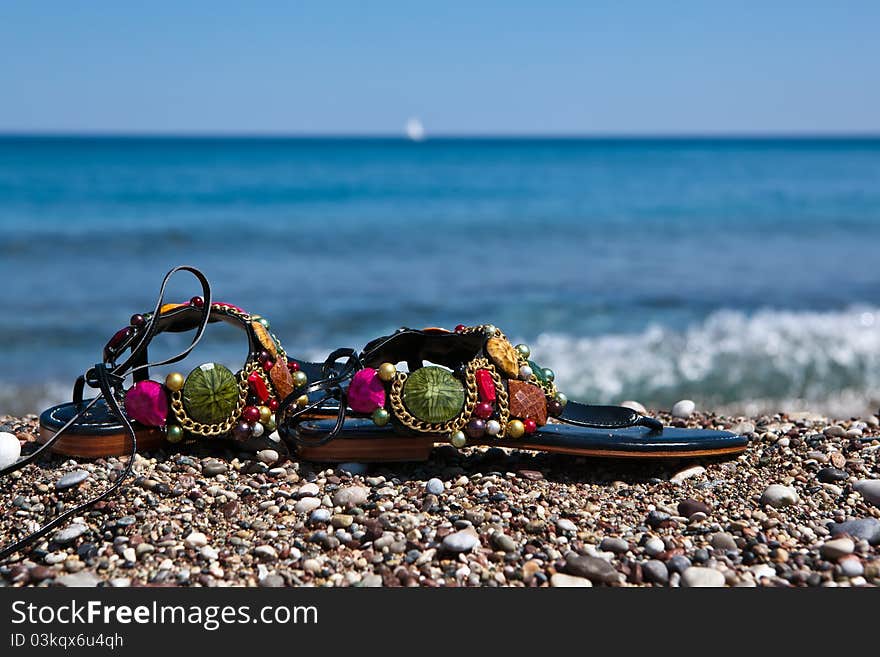 Colorful summer beachwear,open-toe sandals on sand beach. Colorful summer beachwear,open-toe sandals on sand beach