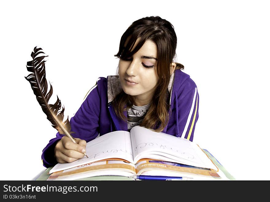 View of a teenager school girl writing on the book with a feather pen. View of a teenager school girl writing on the book with a feather pen.