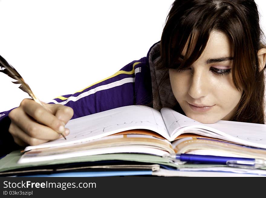 View of a teenager school girl writing on the book with a feather pen. View of a teenager school girl writing on the book with a feather pen.