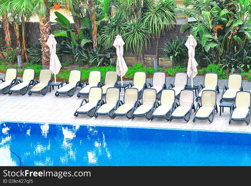 plastic chairs and umbrellas near swimming pool