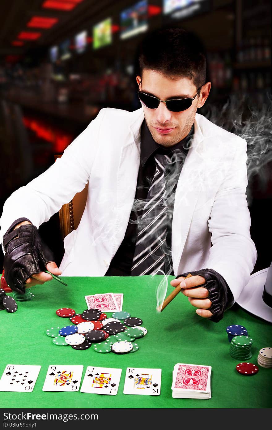 View of a gangster man playing some cards and poker, smoking a Cuban cigar. View of a gangster man playing some cards and poker, smoking a Cuban cigar.