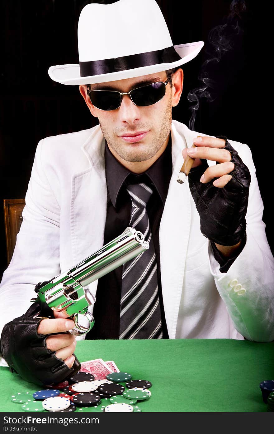 View of a gangster man playing some cards and poker, smoking a Cuban cigar. View of a gangster man playing some cards and poker, smoking a Cuban cigar.