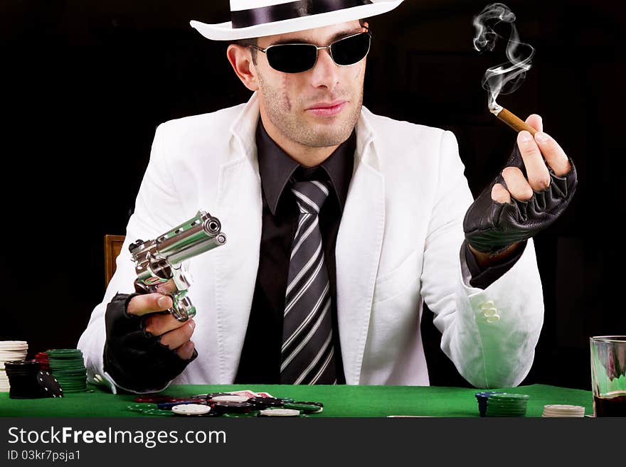 View of a gangster man playing some cards and poker, smoking a Cuban cigar. View of a gangster man playing some cards and poker, smoking a Cuban cigar.