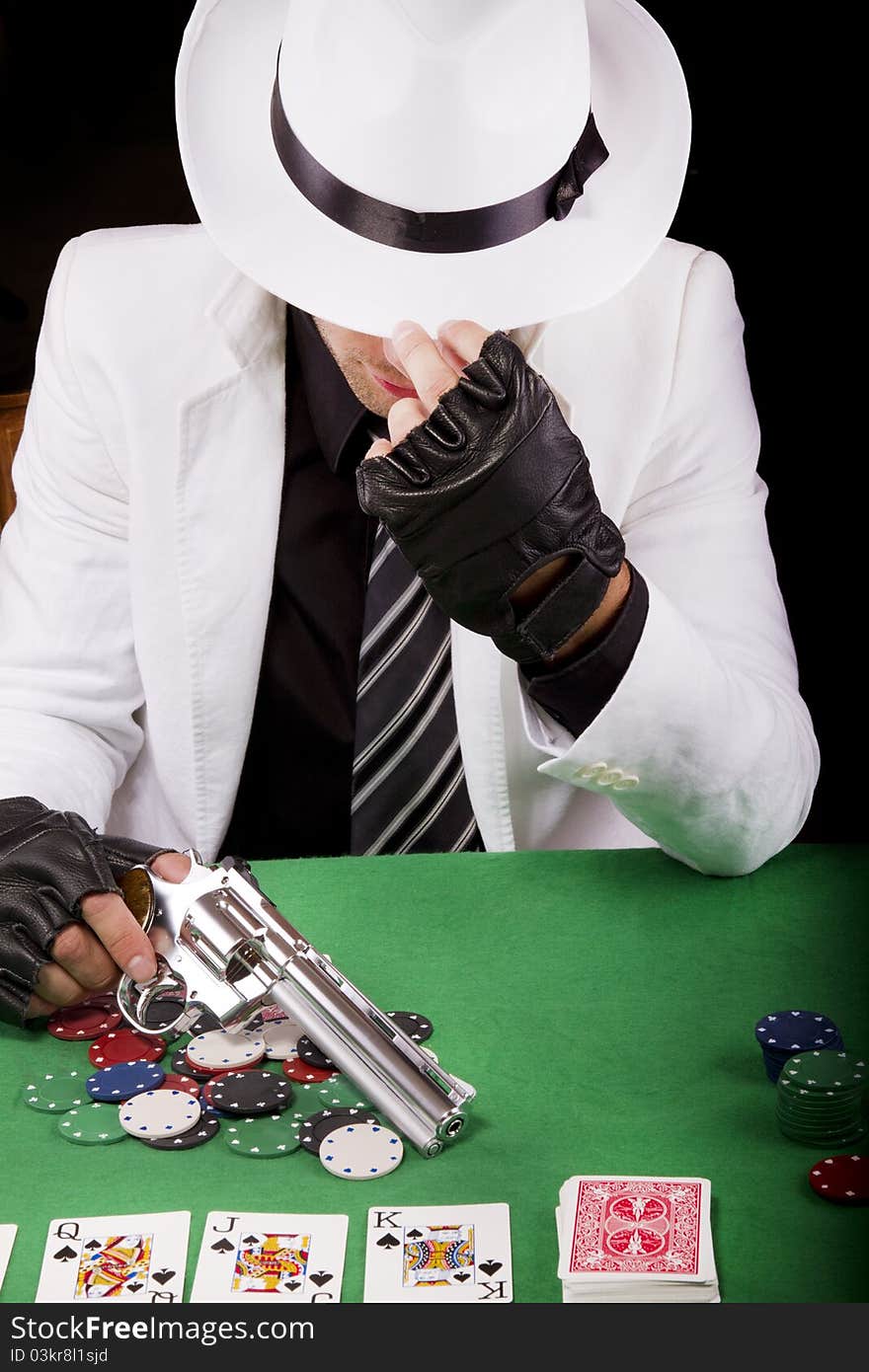 View of a gangster man playing some cards and poker, holding a gun. View of a gangster man playing some cards and poker, holding a gun.