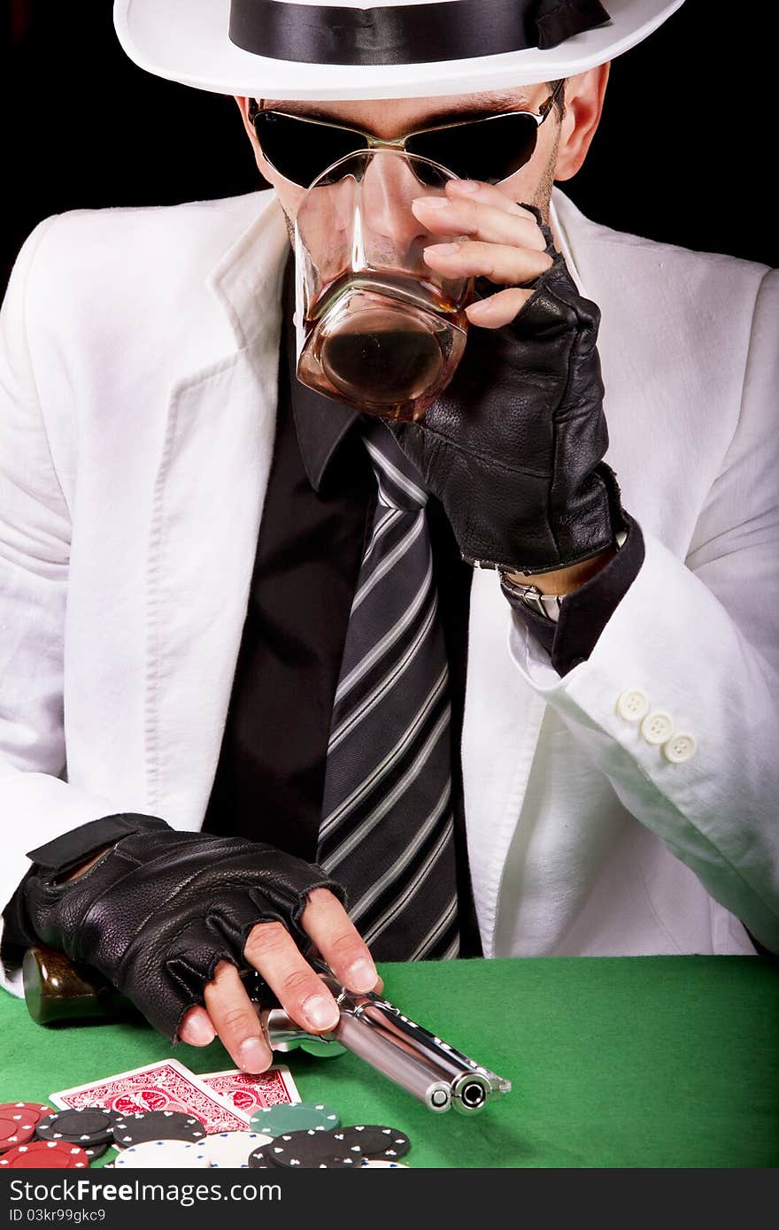 View of a gangster man playing some cards and poker, having a drink. View of a gangster man playing some cards and poker, having a drink.