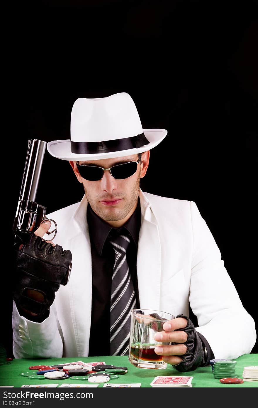 View of a gangster man playing some cards and poker, holding a gun. View of a gangster man playing some cards and poker, holding a gun.