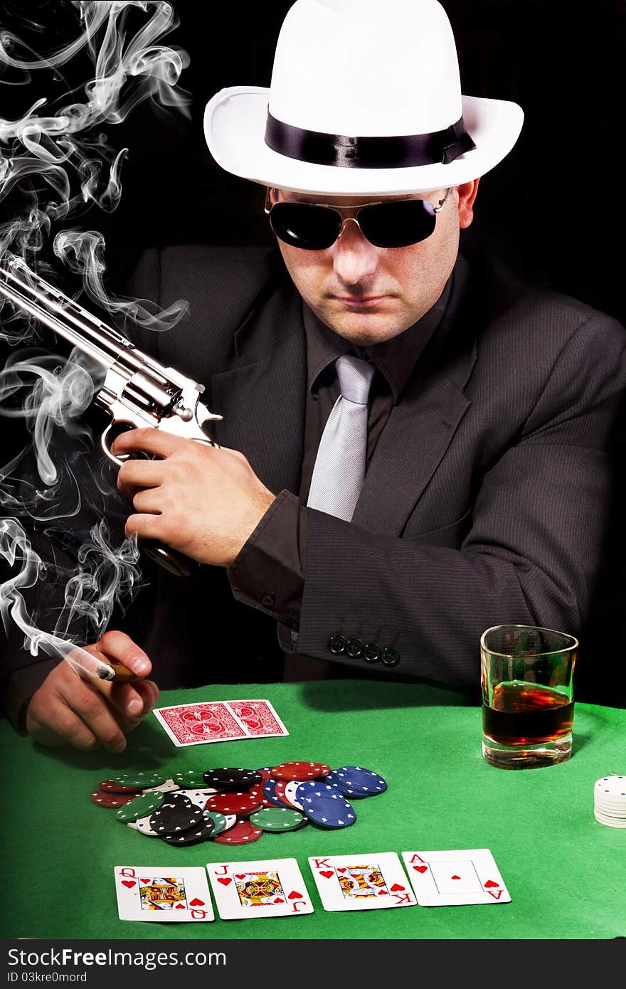 View of a gangster man playing some cards and poker, smoking a Cuban cigar. View of a gangster man playing some cards and poker, smoking a Cuban cigar.