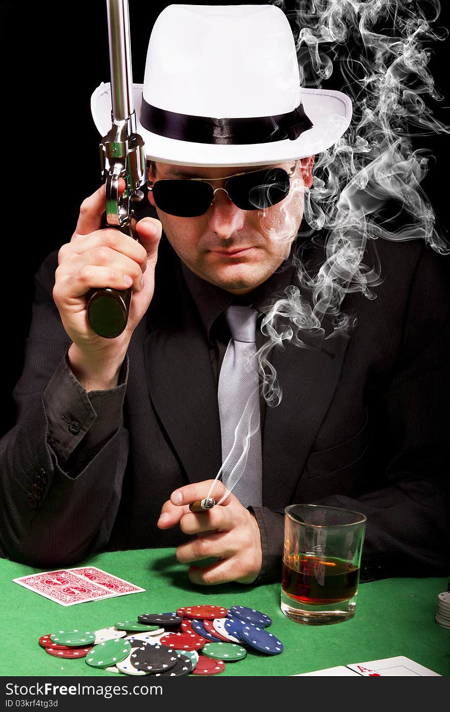 View of a gangster man playing some cards and poker, smoking a Cuban cigar. View of a gangster man playing some cards and poker, smoking a Cuban cigar.