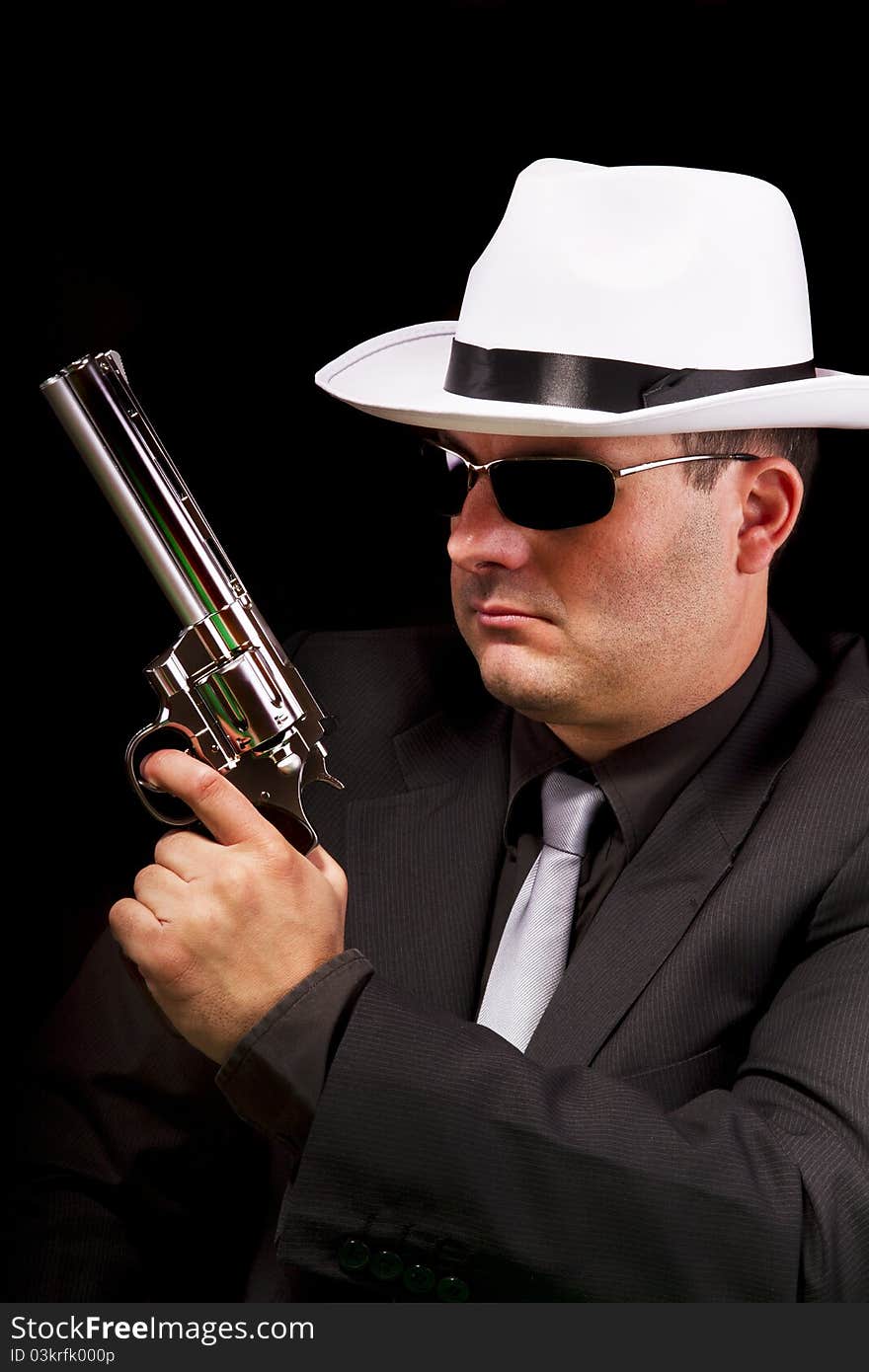 View of a dark suit gangster man holding a gun. View of a dark suit gangster man holding a gun.