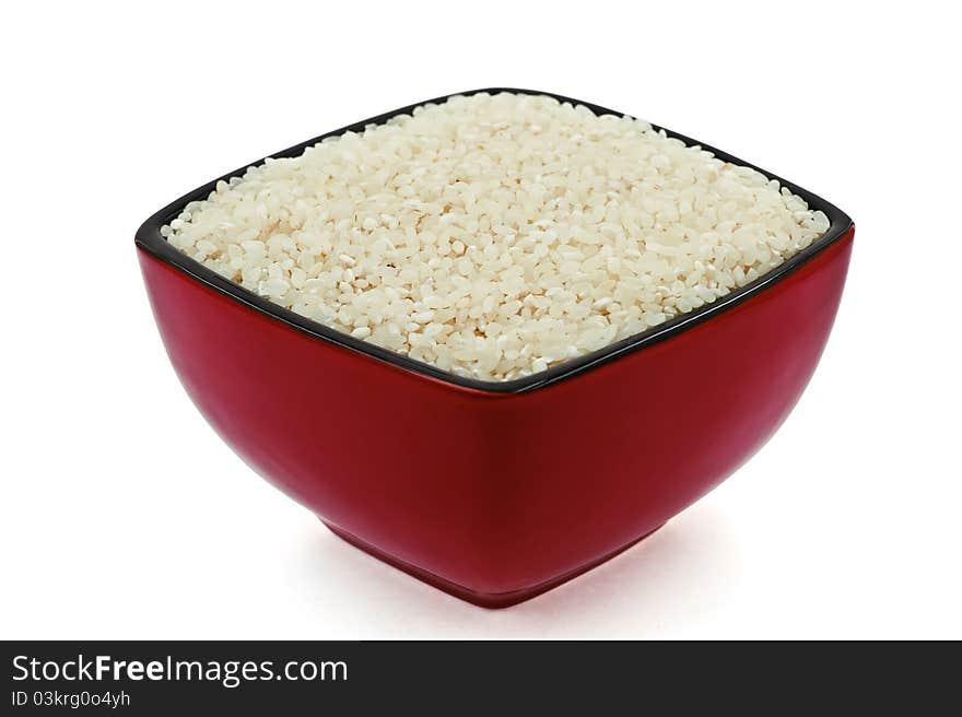 A red-black dish full of raw rice on the white background