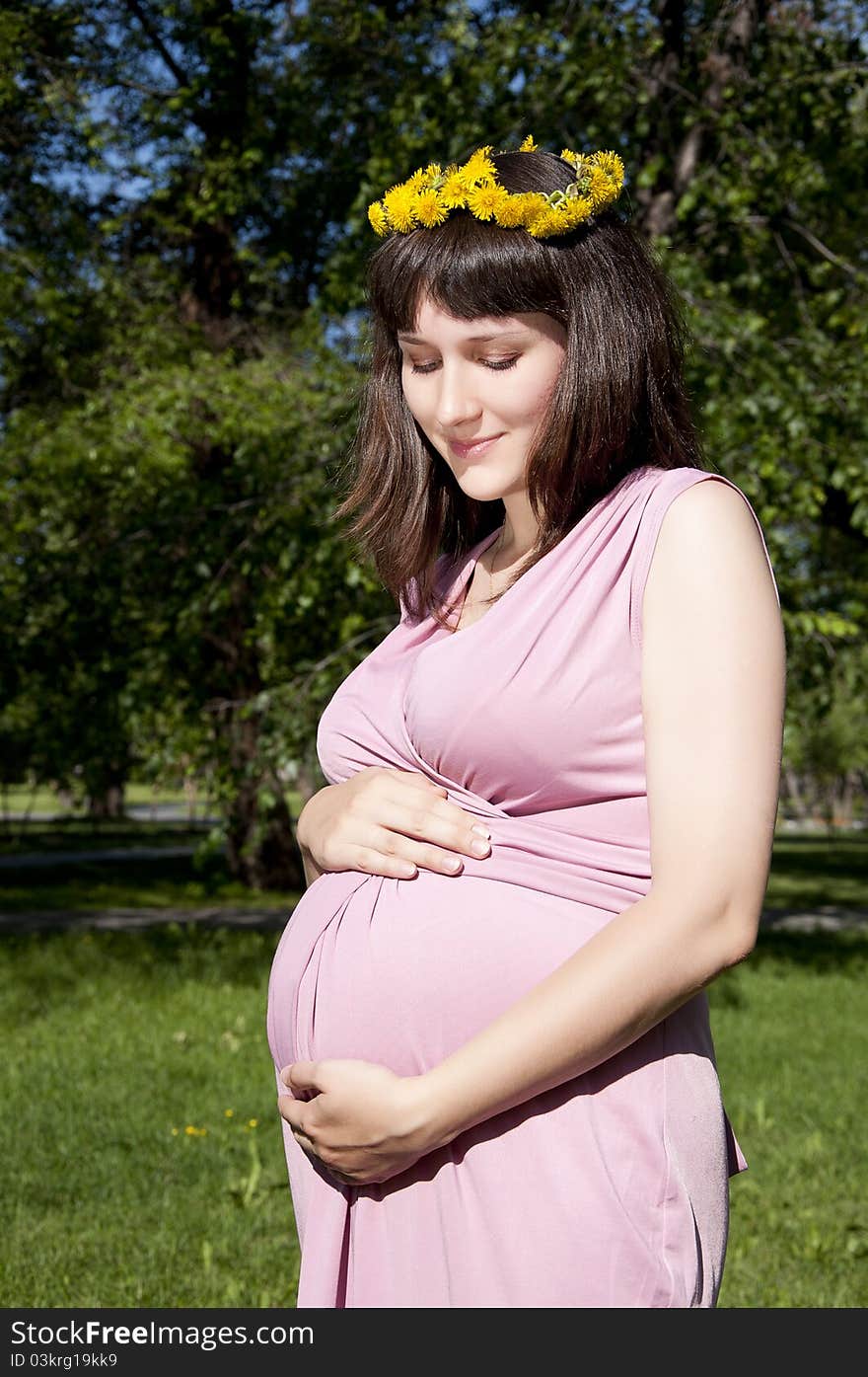 Portrait of the young beautiful girl in park, the girl embraces the stomach. Portrait of the young beautiful girl in park, the girl embraces the stomach