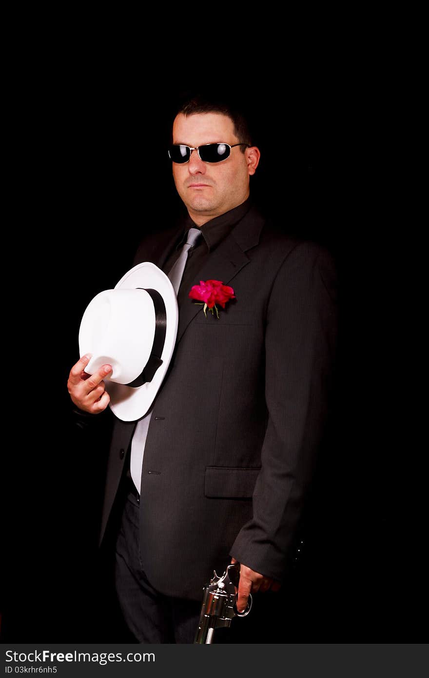 View of a dark suit gangster man holding a gun. View of a dark suit gangster man holding a gun.