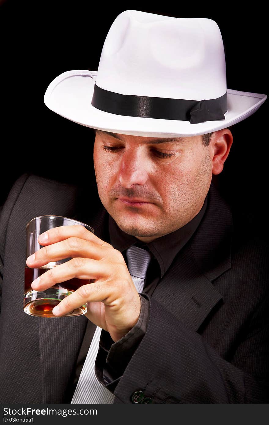 View of a gangster man with white hat drinking some liquor. View of a gangster man with white hat drinking some liquor.