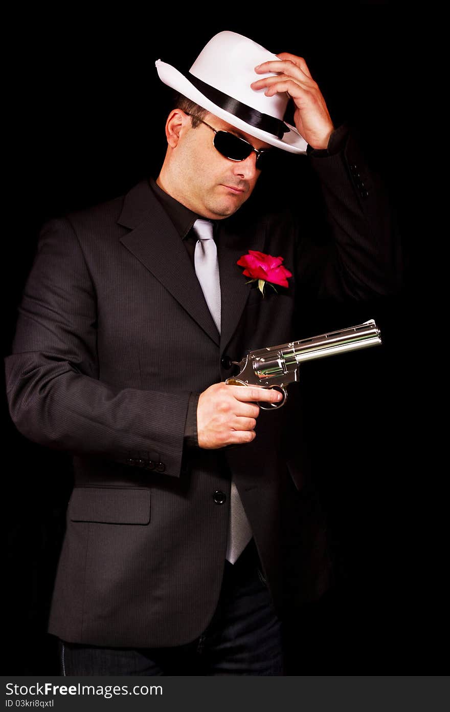 View of a dark suit gangster man holding a gun. View of a dark suit gangster man holding a gun.