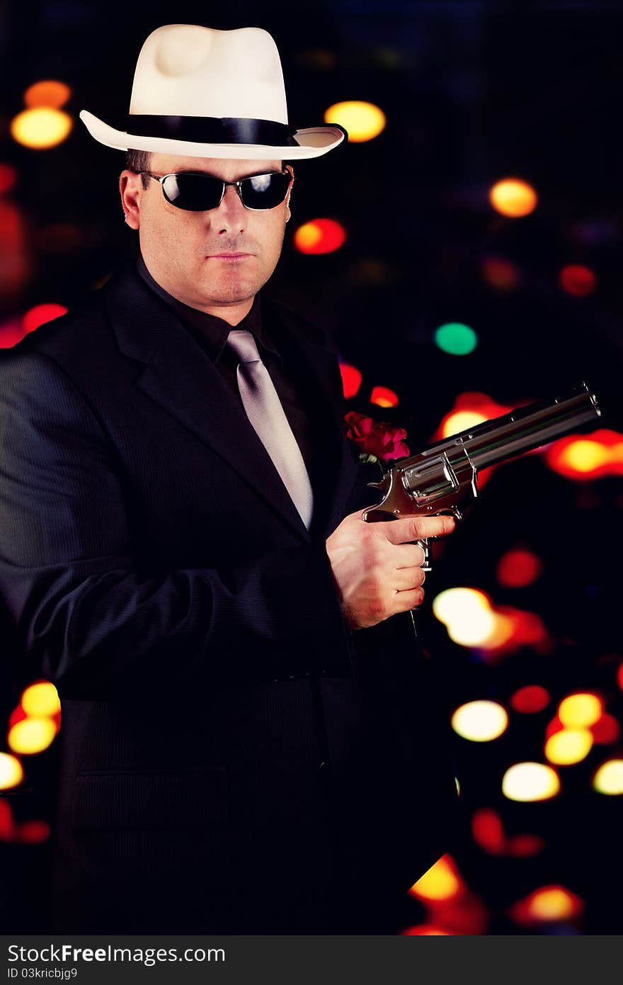 View of a dark suit gangster man holding a gun. View of a dark suit gangster man holding a gun.