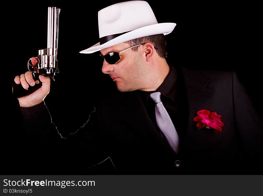 View of a dark suit gangster man holding a gun. View of a dark suit gangster man holding a gun.