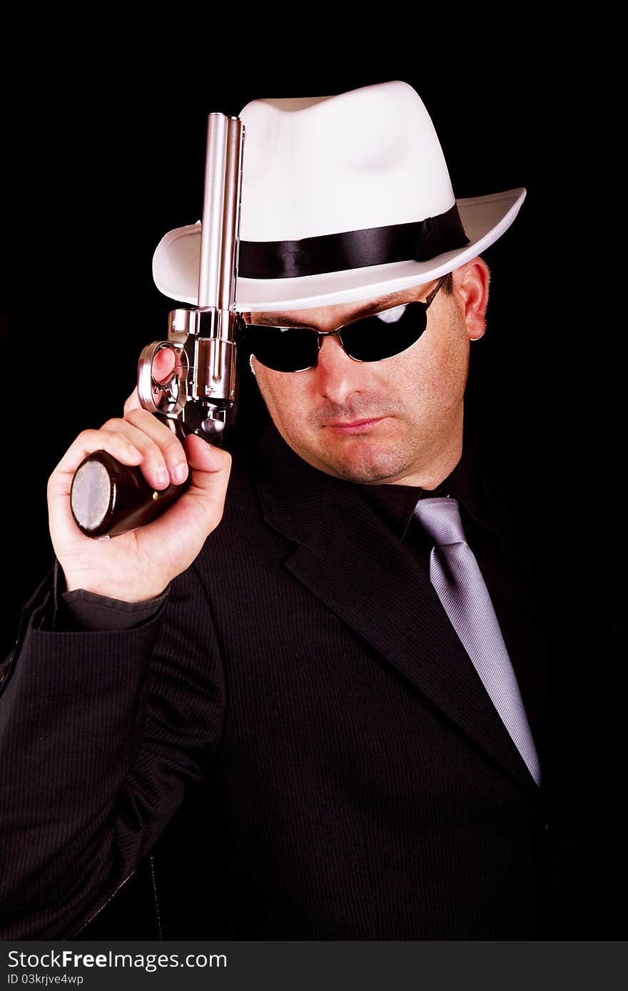 View of a dark suit gangster man holding a gun. View of a dark suit gangster man holding a gun.