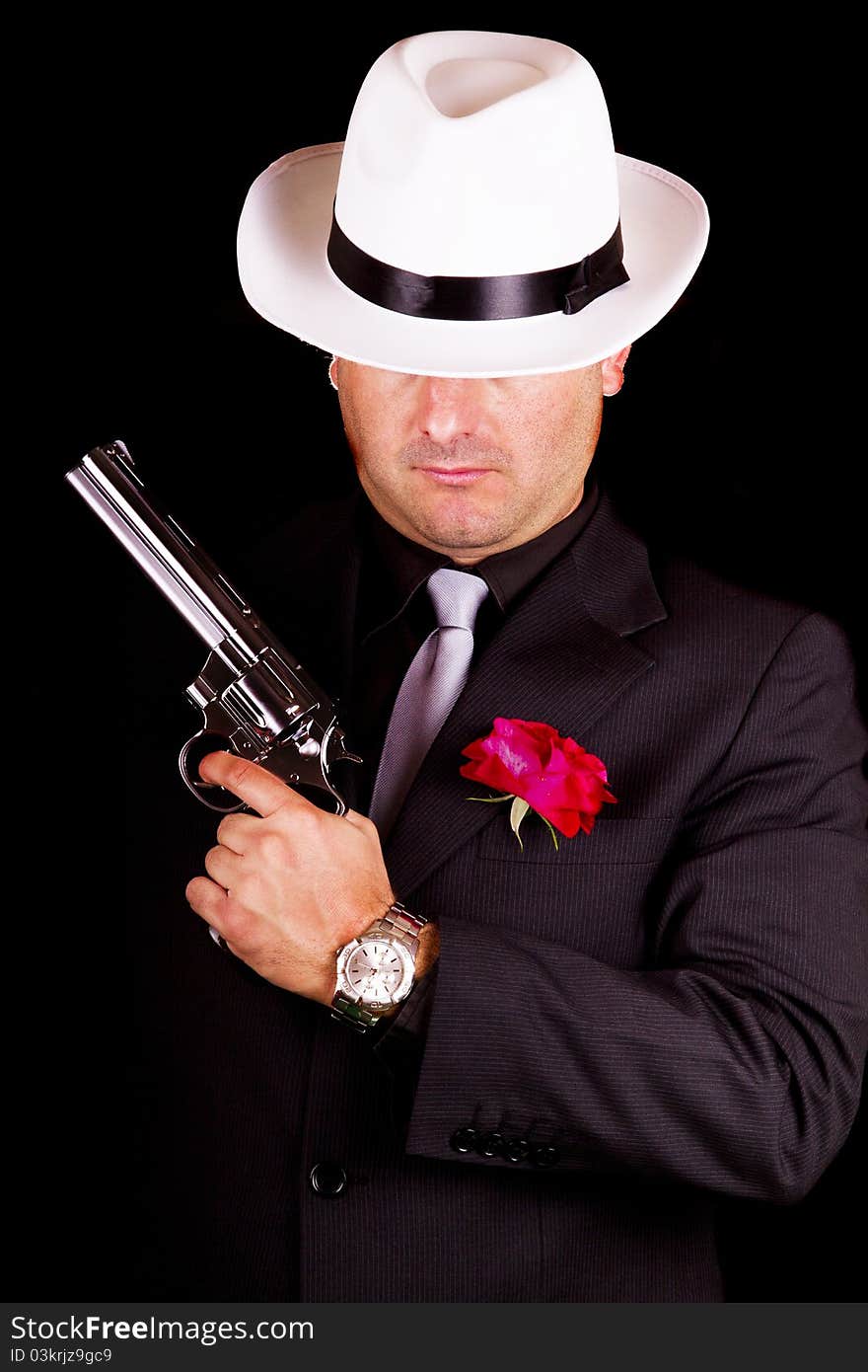 View of a dark suit gangster man holding a gun. View of a dark suit gangster man holding a gun.