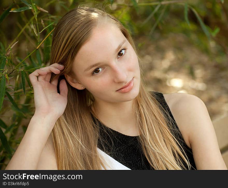 A portrait of a teenager smiling up at the viewer, with trees in the background. A portrait of a teenager smiling up at the viewer, with trees in the background